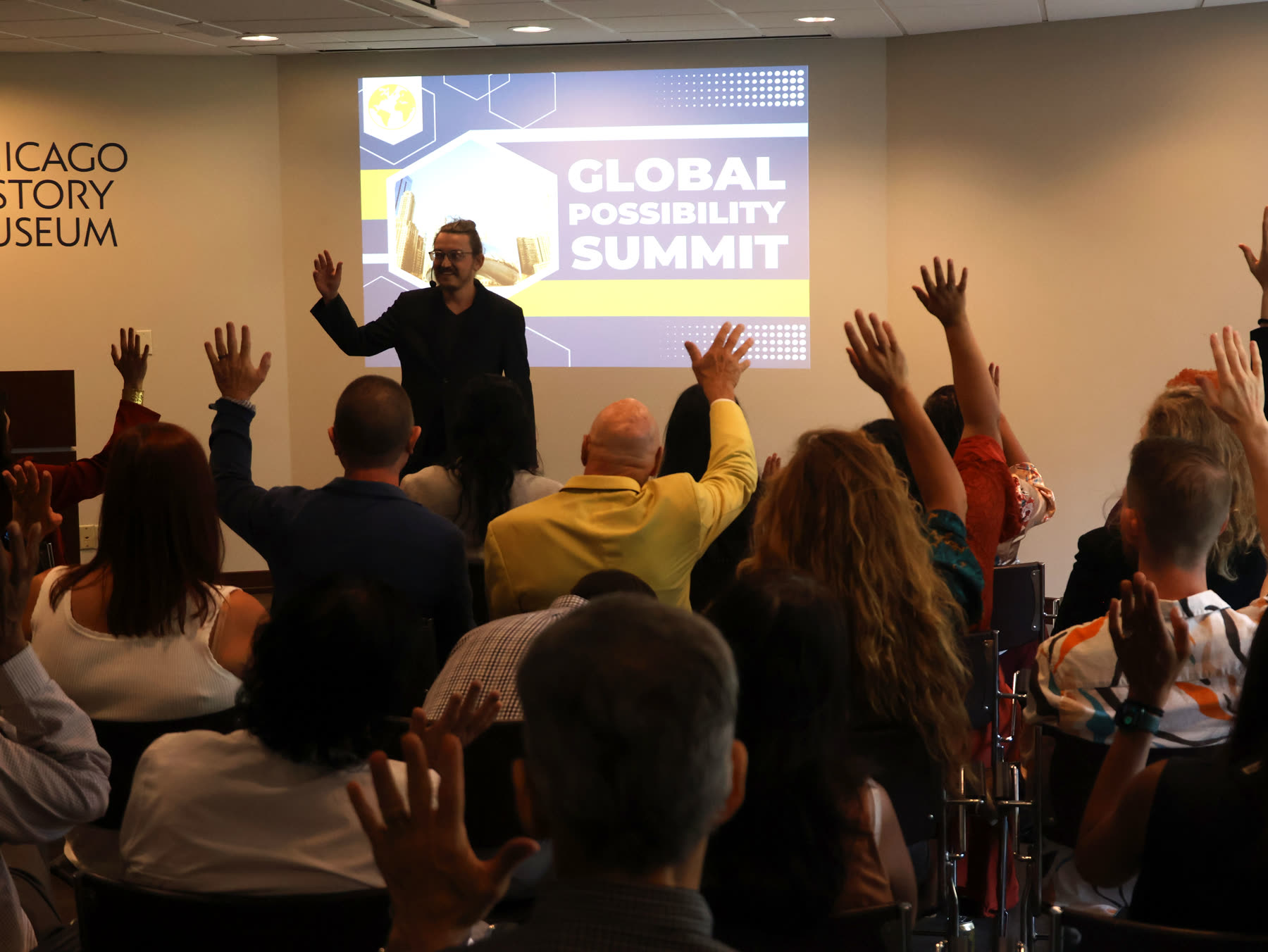 Alex Feldman facilitating a live room with hands raised